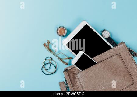 Fashion concept : Flat lay of brown leather woman bag open out with cosmetics, accessories and smartphone on pink background Stock Photo