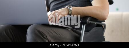 Man sitting in wheelchair working with laptop computer Stock Photo
