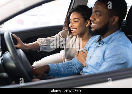 Cheerful Black Couple Testing Car Buying Auto In Dealership Center Stock Photo