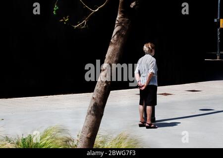 An old woman standing with her back to the sun. Stock Photo