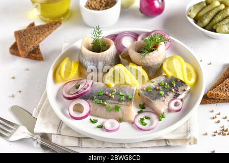 Salted herring with spice and onion on plate. Russian cuisine, close up view Stock Photo