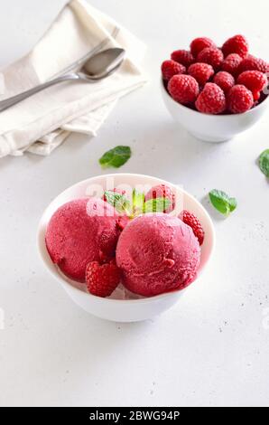 Raspberry ice cream scoop with fresh raspberries in white bowl. Cold summer dessert Stock Photo