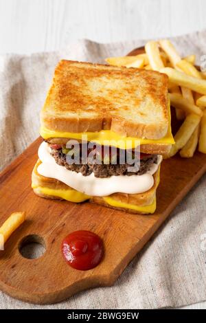 Homemade Grilled Cheese Burger with French Fries on a rustic wooden board, low angle view. Stock Photo