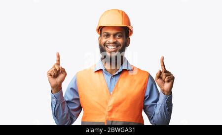 Cheerful Construction Worker Pointing Fingers Up On White Studio Background Stock Photo