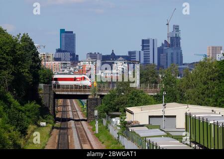 A rail class 800 Azum Train operated by LNER passes in front of Leeds Skyline, as it heads into Leeds City Station Stock Photo
