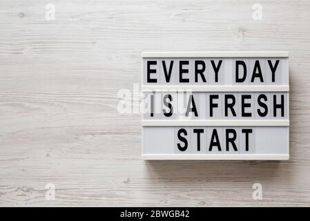'Every day is a fresh start' words on a lightbox on a white wooden surface, top view. Overhead, from above, flat lay. Space for text. Stock Photo