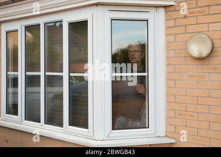 Man looking anxiously out of window Stock Photo