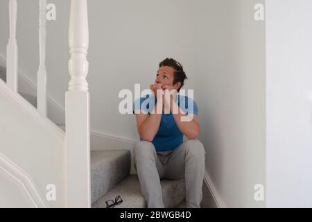 Man struggling with depression sitting on stairs Stock Photo