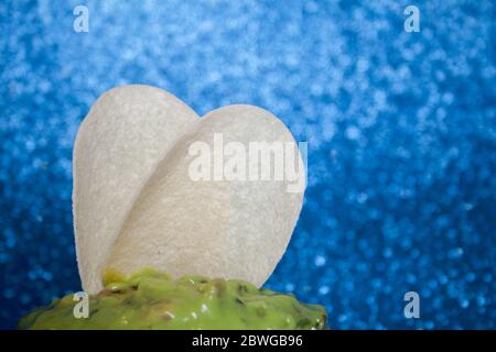 Potato chips with guacamole sauce with green avocado on a blue background. Stock Photo