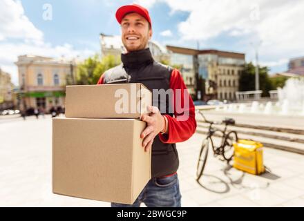 Courier Man Delivering Boxes, Parcels And Food In City Stock Photo