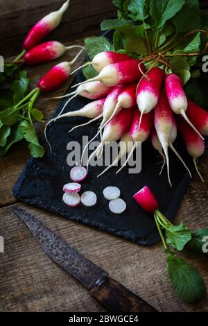 Summer harvested red radish. Organic vegetables. Raw fresh juicy garden radish on a rustic wooden table. Stock Photo