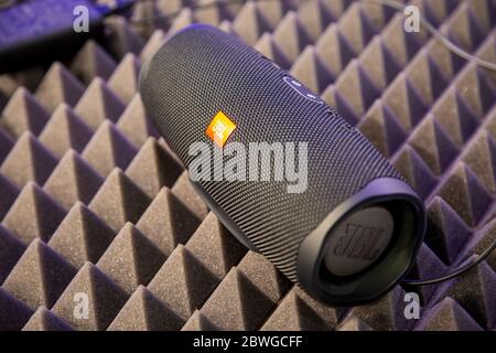 Moscow, Russia - October 04, 2019: close up of black portable bluetooth waterproof music speaker JBL Charge 4 rests on noise reduction cover. soft Stock Photo