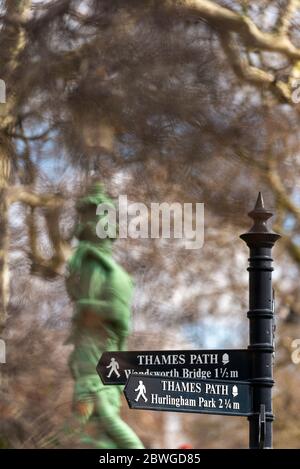 Ornate signpost on the bank of the river thames for the Thames Path with a winter scene and statue in Chelsea London Stock Photo