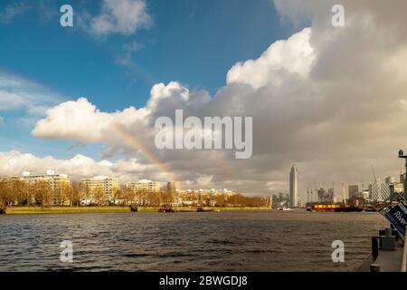 A rainbow over the River Thames from Battersea Power Station Pier with a view of the residential buildings in Vauxhall and Pimlico South West London Stock Photo