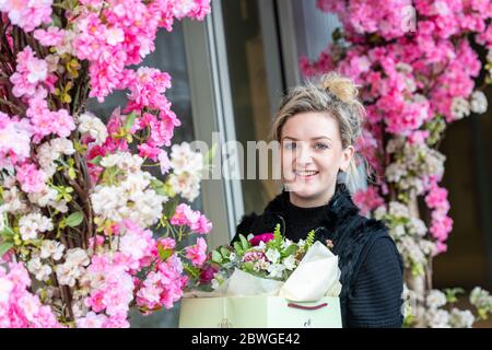 A pretty young florist surrounded by flowers outside her shop in recently redeveloped Battersea Power Station area in South West London. Stock Photo