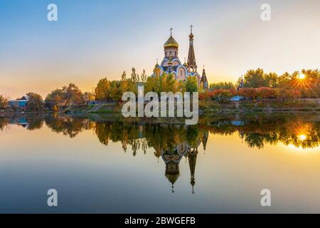 Reflection of a Russian orthodox church in Almaty, Kazakhstan, in the fall at the sunset. It is known as Church of exaltation of the holy cross. Stock Photo