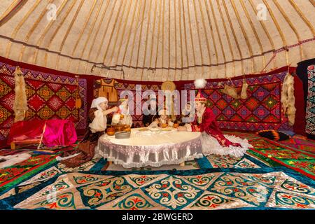 Kazakh people in traditional costumes in a nomadic tent known as yurt, drinking Kymyz, traditional drink made with horse milk, in Almaty, Kazakhstan Stock Photo