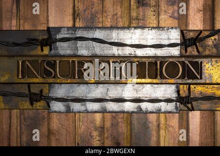 Photo of real authentic typeset letters forming Insurrection text with barbed wire on vintage textured silver grunge copper and gold background Stock Photo