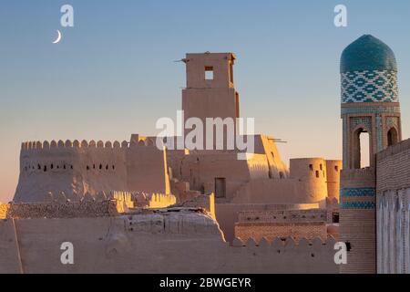 Tower and the old walls of the ancient city of Khiva with crescent moon in the sky, Uzbekistan Stock Photo