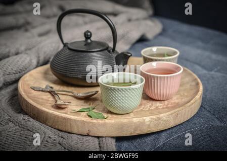 Black iron asian tea set on wooden tray on knitted plaid closeup Stock Photo