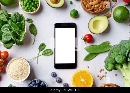 Creative flat lay with vegetarian meal ingredients and smartphone with empty screen; copy space. Raw vegan food concept, healthy groceries delivery. O Stock Photo