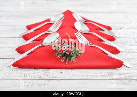 Red napkins in the shape of a Christmas tree with forks and spoons on wooden background closeup Stock Photo