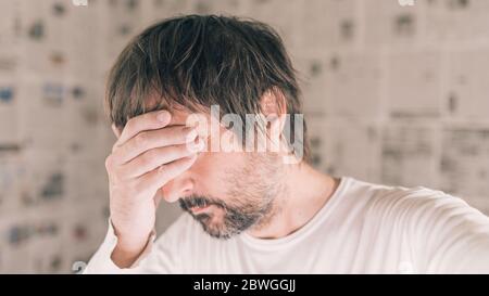 Depressed man in infodemic concept, adult male with head in hands crying confused Stock Photo
