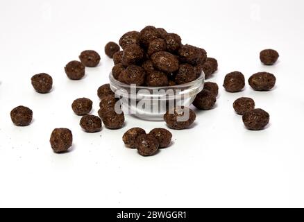 Choco pops or Chocolate balls grouped in a transparent bowl for morning healthy calorie breakfast and few placed on a surface Stock Photo