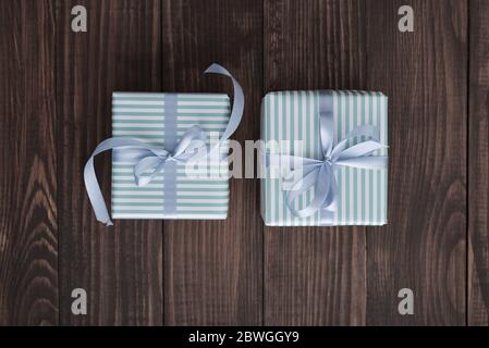 Striped gift boxes with blue ribbon on wooden background top view Stock Photo