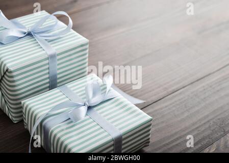 Striped gift box with blue ribbon on wooden background closeup Stock Photo