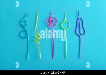 Multi-colored semi-transparent in many shapes straw. Drinking straws in the colors blue, purple, pink on a blue background Stock Photo