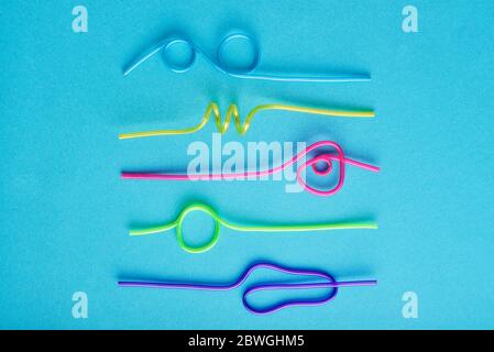Multi-colored semi-transparent in many shapes straw. Drinking straws in the colors blue, purple, pink on a blue background Stock Photo