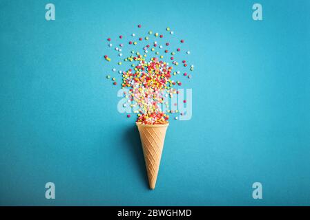 Celebration concept. Ice cream cone  with colorful stars confetti on a blue background, top view Stock Photo