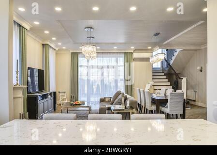 View from kitchen on living room interior in yellow and green colors features gray sofa and  tv. Stock Photo