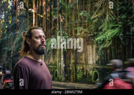 Portrait of  young man with beard and long hair  near  road in Ubud, Indonesia Stock Photo