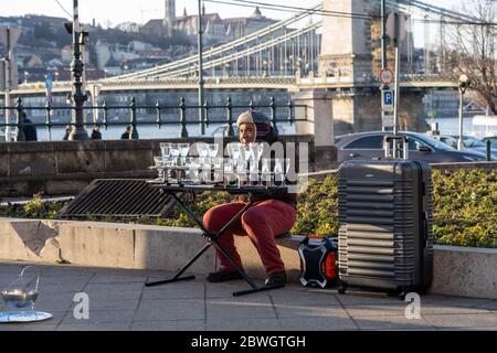 Budapest, Hungary - Feb 8, 2020: Street artist outside Gresham Palace during sunset Stock Photo