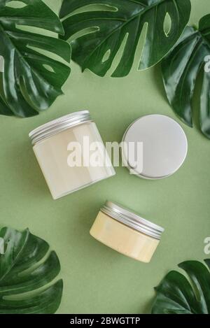Bottles with spa cosmetic products on green background, top view. Beauty salon treatments concept. Stock Photo