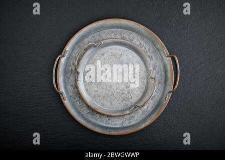 Vintage metal round tray on black slate background, top view Stock Photo