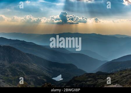 Panoramic view over a glacier lake valley at sunset with amazing rays of light from Retezat Mountains, Romania Stock Photo