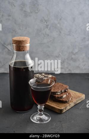 Traditional Russian drink kvass made from bread, rye malt, sugar and water. Kvass in bottle with rye bread and glass on a gray background. Stock Photo