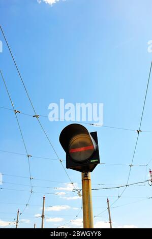 Stop light on tramway against overhead cables and sky Stock Photo