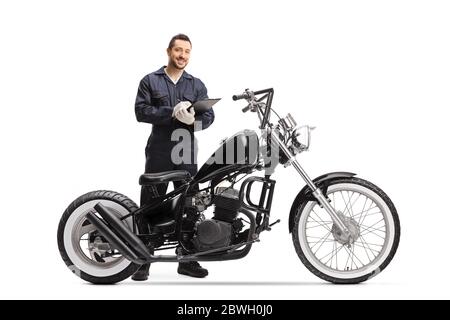 Motorbike mechanic standing behind a chopper and holding a clipboard isolated on white background Stock Photo