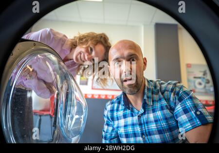 laundry, surprised look men and women into the washing machine or clothes dryer Stock Photo