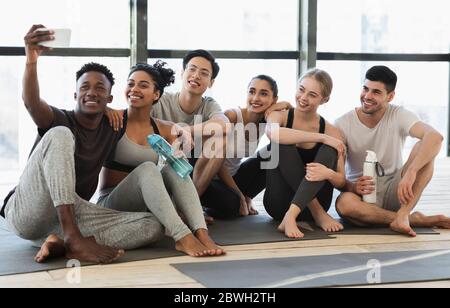 Happy multicultural friends taking selfie on smartphone after fitness training Stock Photo
