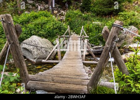 Old wooden bridge crossing over mountain stream in Romanian mountains Stock Photo