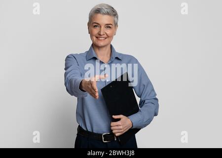Recruitment concept. Friendly middle-aged HR manager extending hand for handshake at camera Stock Photo
