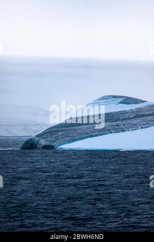 layered iceberg, grounded  in Maxwell Bay, Fildes, King George Island, South Shetland Islands, Southern Ocean Stock Photo