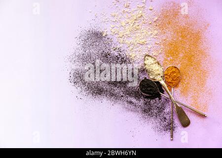 Color explosion of black white and orange - activated carbon, coconut and turmeric from three silver spoons Stock Photo