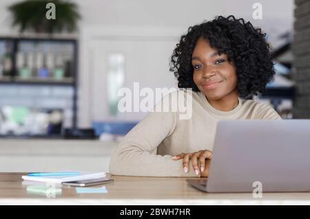 Pretty african girl posing at cafe while working with laptop Stock Photo