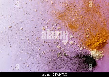 Violet background with colorful explosion of ingredients - activated carbon, coconut and turmeric Stock Photo